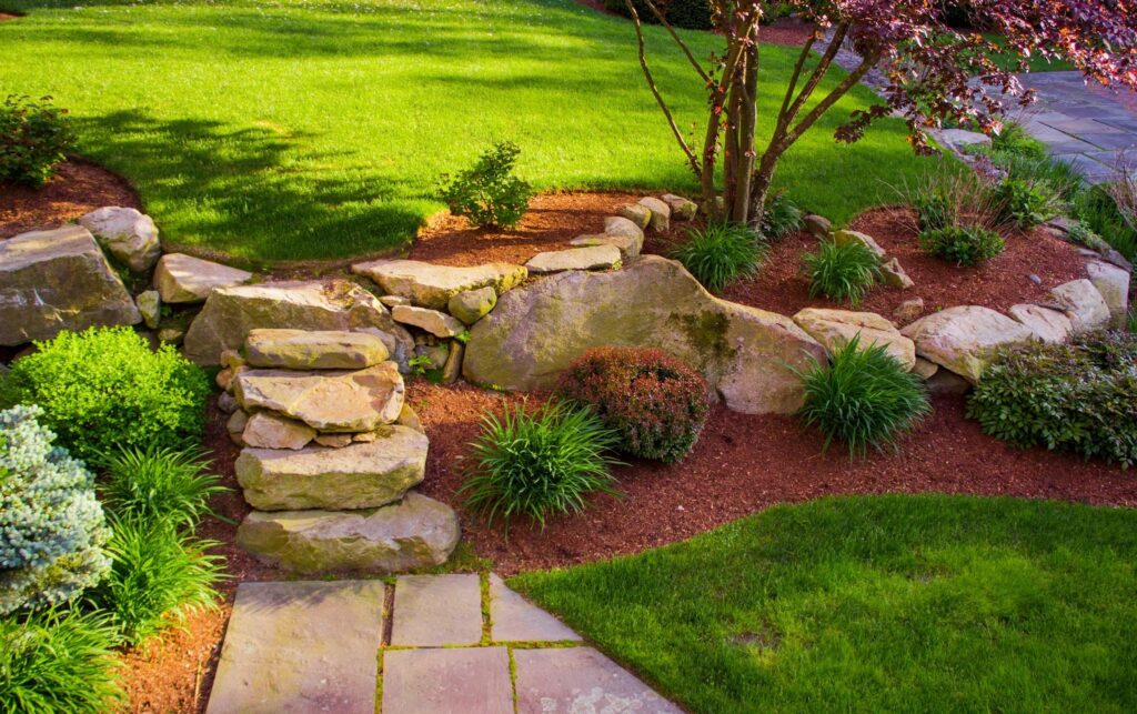 A landscape display with rocks and a flowerbed in a yard.